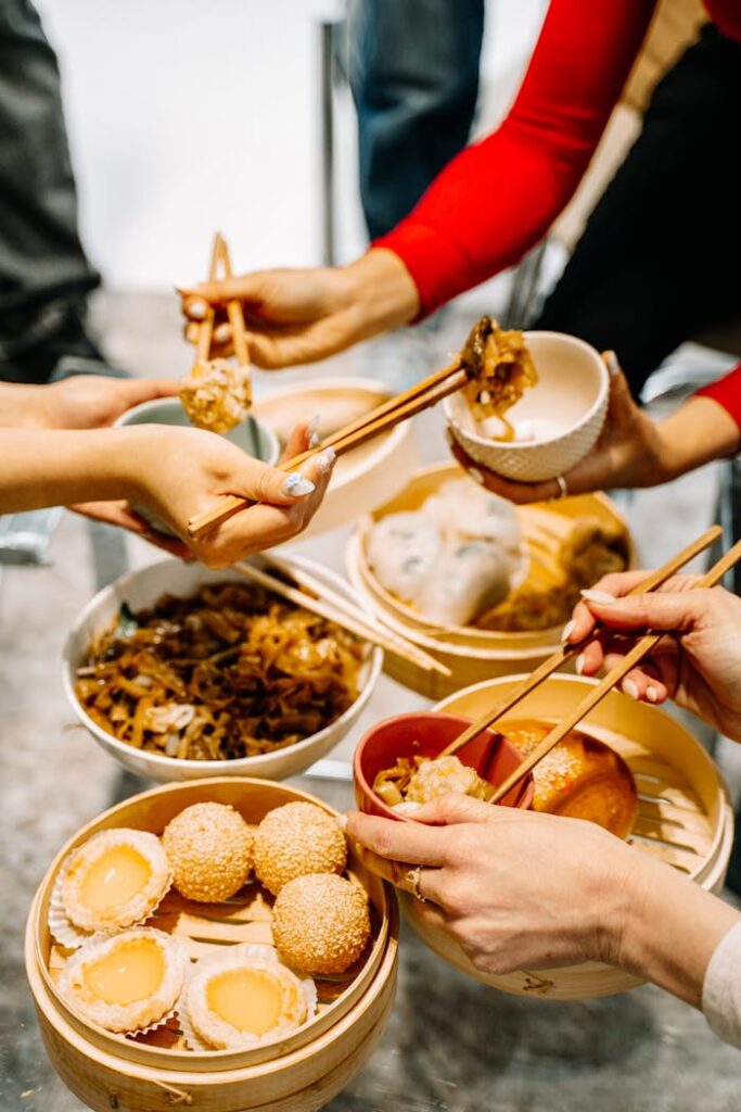 A group sharing a vibrant dim sum meal with chopsticks, highlighting cultural cuisine.